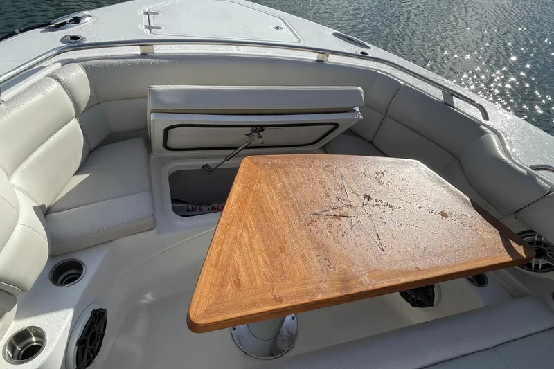 Slide: The Image of 2022 Boston Whaler 350 Realm boat interior with wooden table and cushioned seating. - 32