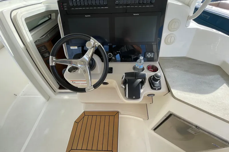 Slide: The Image of 2022 Boston Whaler 350 Realm helm with steering wheel, controls, and navigation screens. - 6