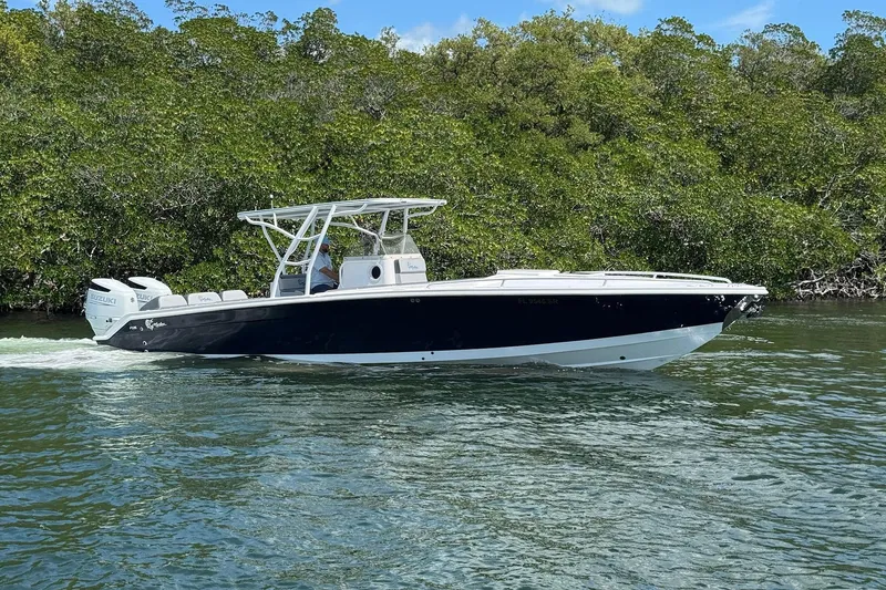 The Image of 2003 Marlago FS 35 Center Console boat cruising on water near lush greenery. - 1