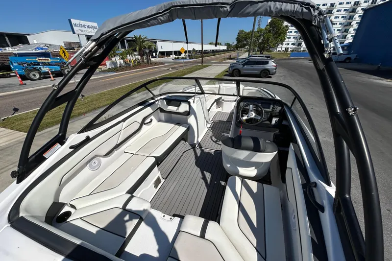 Slide: The Image of 2017 Yamaha Boats AR210 interior with seating and steering wheel, parked near a marina. - 4