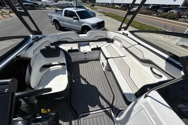 Slide: The Image of 2017 Yamaha Boats AR210 interior with seating and steering, parked near a white truck. - 7