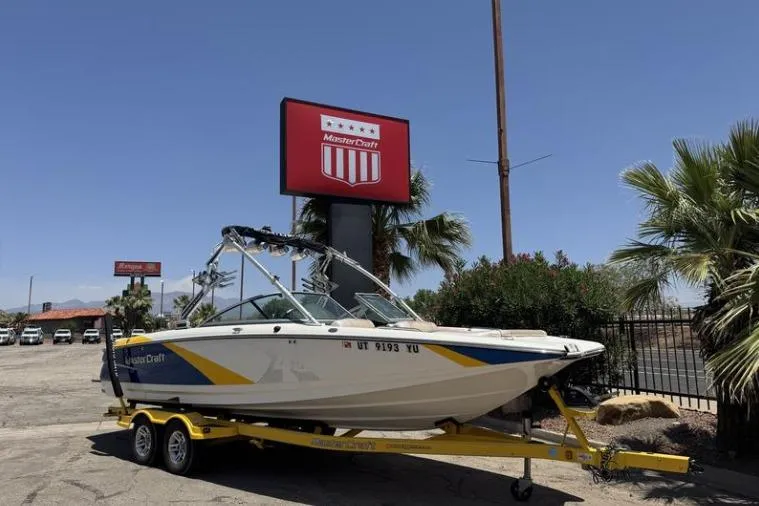 The Image of 2011 MasterCraft X-45 boat on yellow trailer, parked near dealership sign. - 1