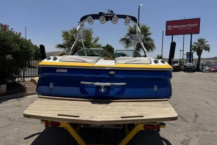 Slide: The Image of 2011 MasterCraft X-45 boat, blue and yellow, parked outdoors near dealership sign. - 7