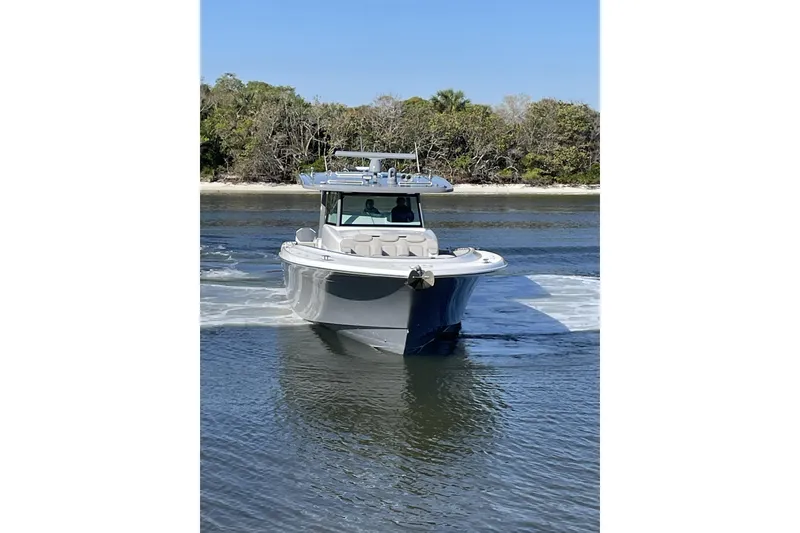 Slide: The Image of 2025 HCB 56 Suenos boat cruising on calm water near a forested shoreline. - 2