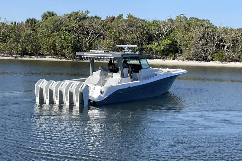 Slide: The Image of 2025 HCB 56 Suenos boat with multiple engines on calm water near a forested shoreline. - 5