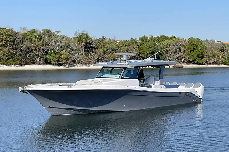 The Image of 2025 HCB 56 Suenos luxury boat cruising on calm water near a forested shoreline. - 0