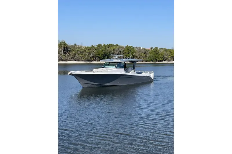 Slide: The Image of 2025 HCB 56 Suenos luxury boat cruising on calm waters near a forested shoreline. - 1