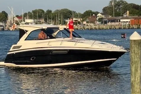 The Image of 2015 Regal 35 Sport Coupe cruising on a sunny day near a marina. - 0