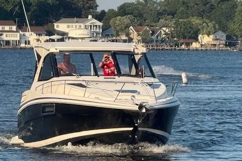 Slide: The Image of 2015 Regal 35 Sport Coupe cruising on a scenic lake with waterfront homes. - 2