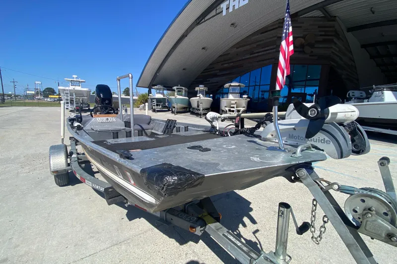 Slide: The Image of 1979 Monark 1648 Jon boat on trailer, equipped with Motorguide motor, parked outside dealership. - 9