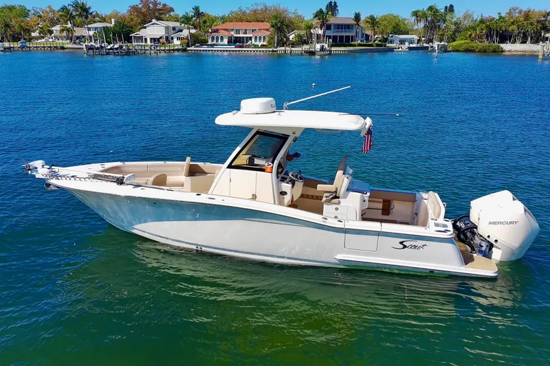 The Image of 2024 Scout 277 LXF boat on clear blue water near waterfront homes. - 0