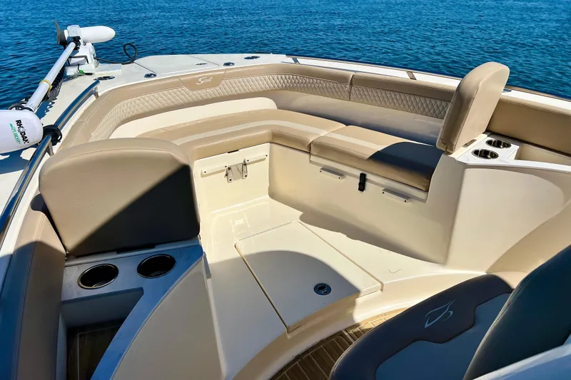 Slide: The Image of 2024 Scout 277 LXF boat interior with beige seating and cup holders on blue water. - 16