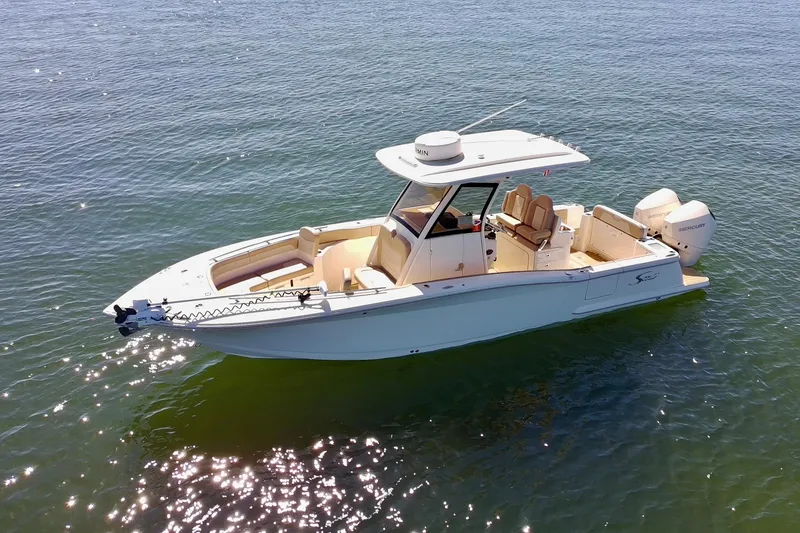 Slide: The Image of 2024 Scout 277 LXF boat on calm water, showcasing sleek design and twin Mercury engines. - 2