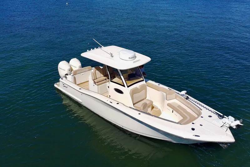 Slide: The Image of 2024 Scout 277 LXF boat on calm blue water, showcasing sleek design and twin engines. - 3