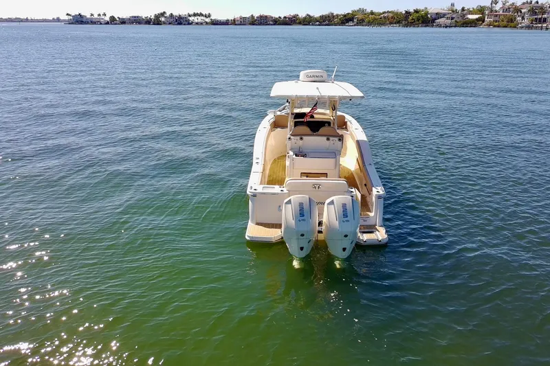 Slide: The Image of 2024 Scout 277 LXF boat on calm water, rear view with twin engines. - 6