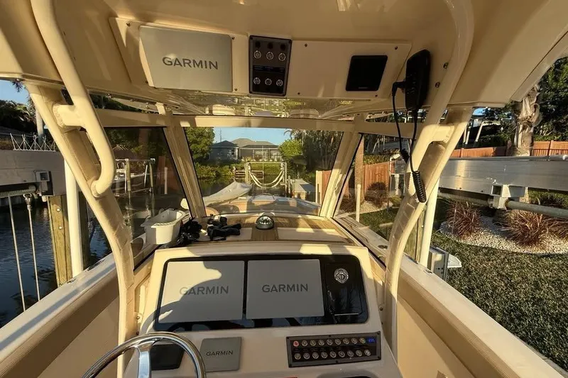 Slide: The Image of 2024 Scout 277 LXF boat cockpit with Garmin navigation system, docked in a scenic marina. - 9