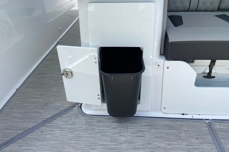 Slide: The Image of 2026 Monterey Elite 30 OB boat interior with open storage compartment and trash bin. - 16