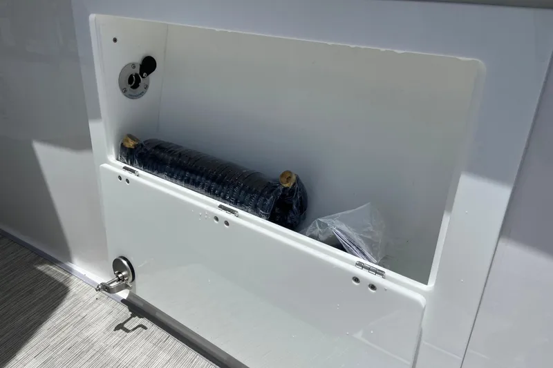Slide: The Image of Storage compartment in 2026 Monterey Elite 30 OB boat, featuring secure latch and interior contents. - 30