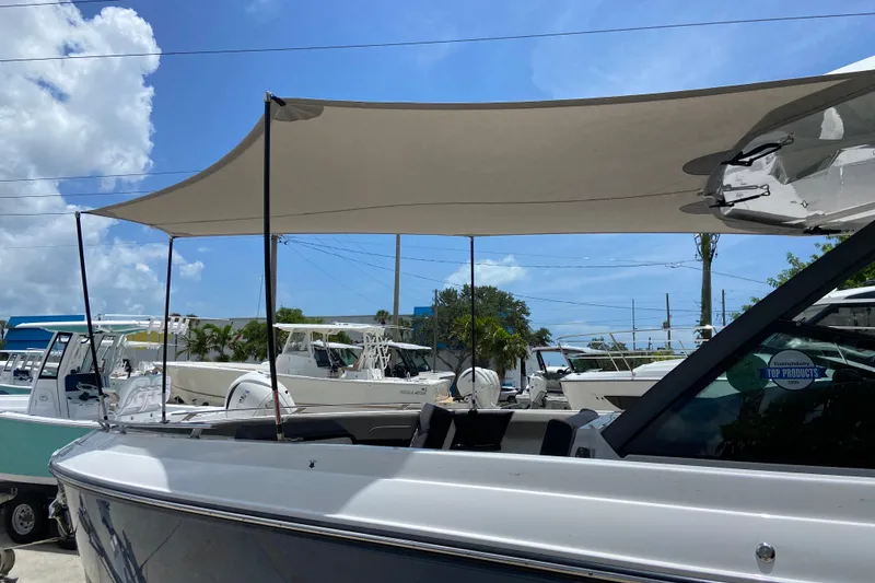 Slide: The Image of 2026 Monterey Elite 30 OB boat with sunshade, parked outdoors under blue sky. - 38