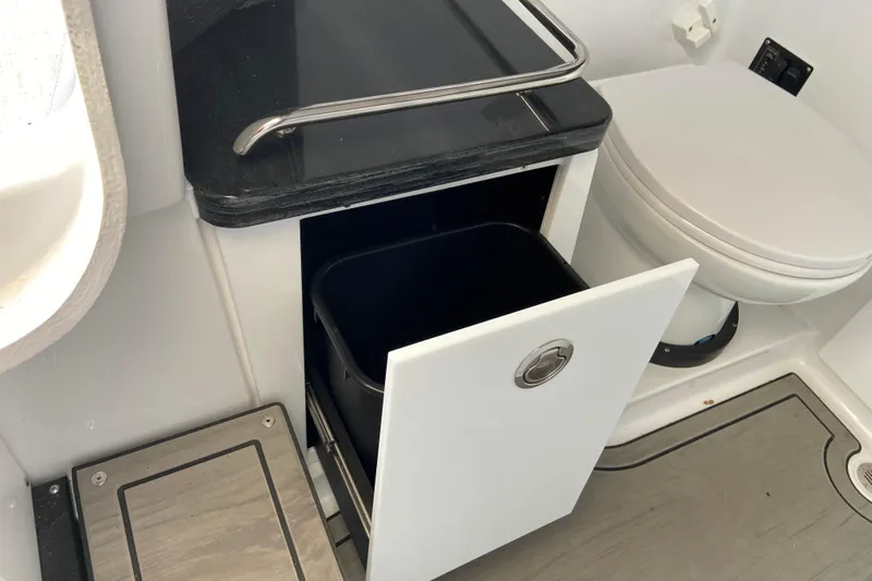 Slide: The Image of Interior of 2026 Monterey Elite 30 OB boat featuring a compact bathroom with storage. - 50