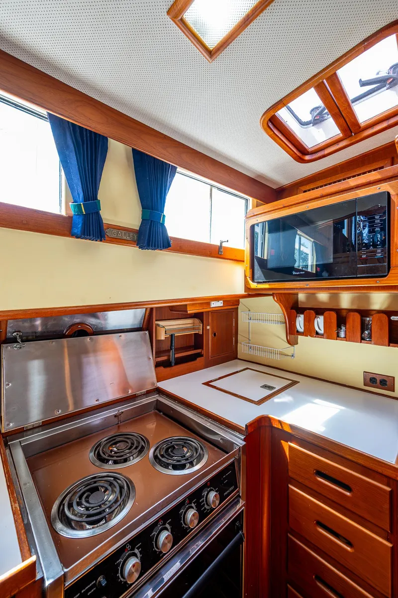 Slide: The Image of 1990 Grand Banks 46 Classic yacht kitchen with stove, microwave, and wooden cabinetry. - 32