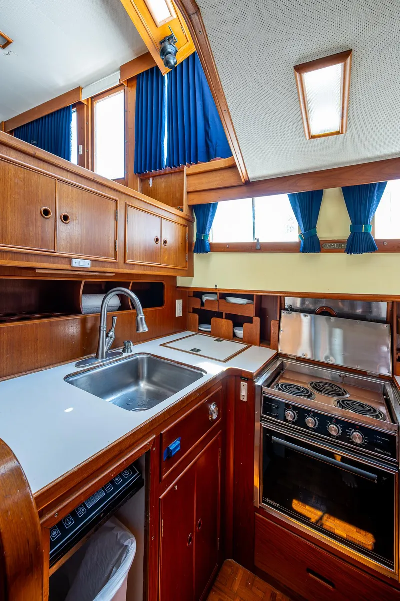 Slide: The Image of 1990 Grand Banks 46 Classic yacht kitchen with wood cabinetry, sink, and stove. - 33