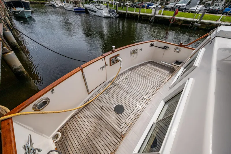 Slide: The Image of Grand Banks 46 Classic 1990 yacht deck with wooden flooring, docked by the water. - 6