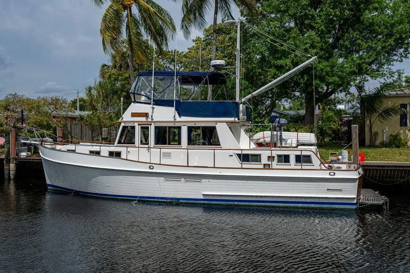 Slide: The Image of Grand Banks 46 Classic 1990 yacht docked by palm trees and water. - 65