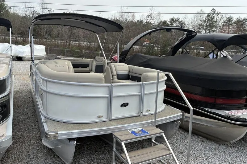 The Image of 2021 Barletta C22UC pontoon boat with beige seating and canopy, parked on gravel. - 0
