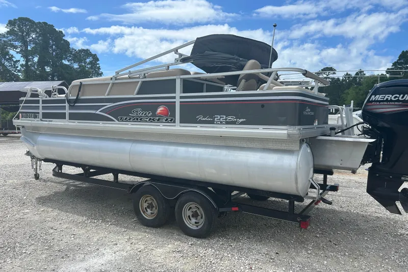 The Image of 2015 Sun Tracker Party Barge 22 Tritoon on trailer, parked outdoors under blue sky. - 0
