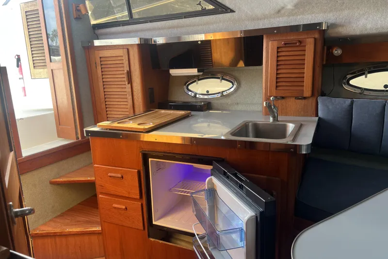 Slide: The Image of Interior of a 1985 Tiara 25 boat featuring a compact kitchen with wooden cabinetry. - 13