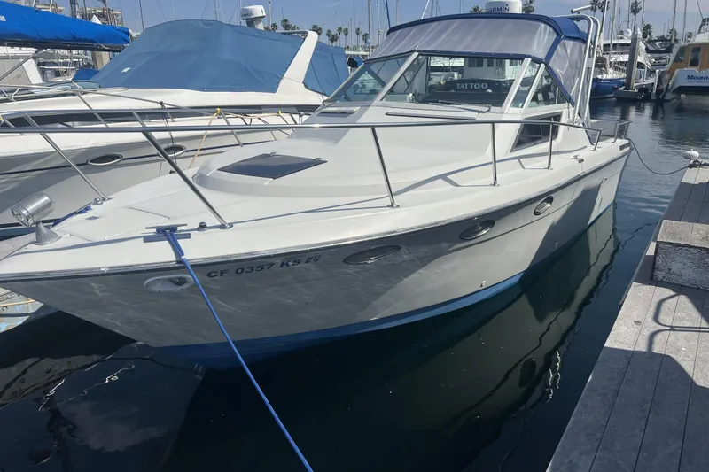 Slide: The Image of 1985 Tiara 25 boat docked at marina, featuring sleek design and blue canopy. - 2