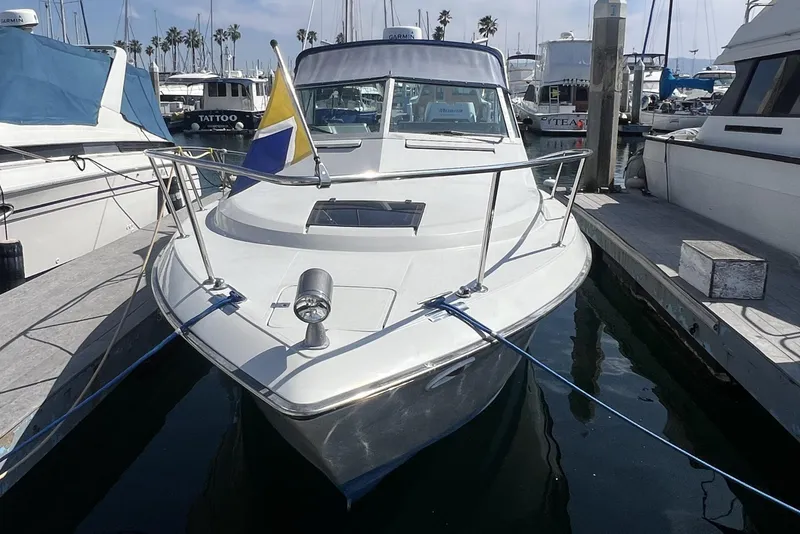 Slide: The Image of 1985 Tiara 25 boat docked at marina with flag and clear sky. - 4