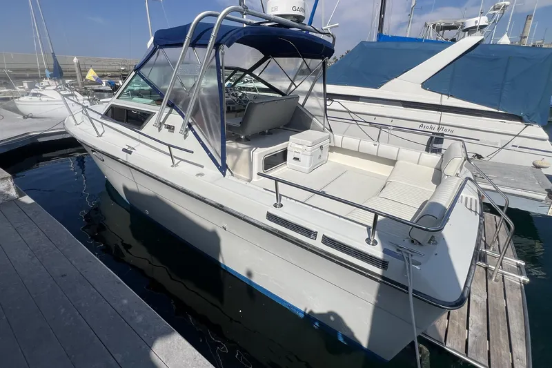 Slide: The Image of 1985 Tiara 25 boat docked at marina, featuring blue canopy and spacious seating area. - 5