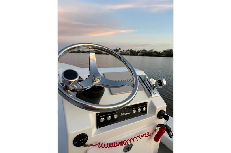 Slide: The Image of Steering wheel of 1988 Lake & Bay Boca Grande 20 boat at sunset on a calm lake. - 10