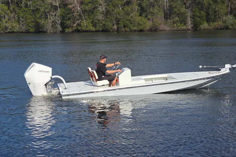 Slide: The Image of 1988 Lake & Bay Boca Grande 20 boat cruising on a calm lake with lush forest backdrop. - 28
