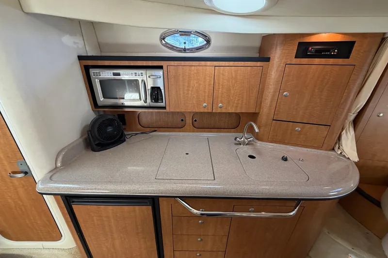 Slide: The Image of 2006 Sea Ray 340 Sundancer galley with microwave, sink, and wooden cabinetry. - 16