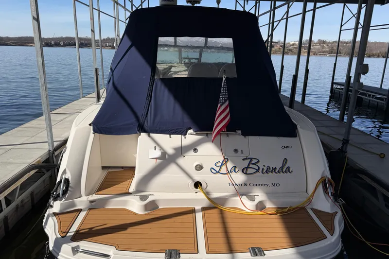 Slide: The Image of 2006 Sea Ray 340 Sundancer docked, featuring a navy canopy and American flag. - 5