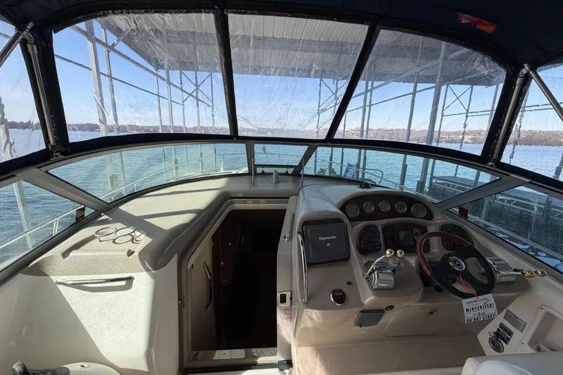 Slide: The Image of 2006 Sea Ray 340 Sundancer cockpit with steering wheel and navigation controls, docked on a sunny day. - 7