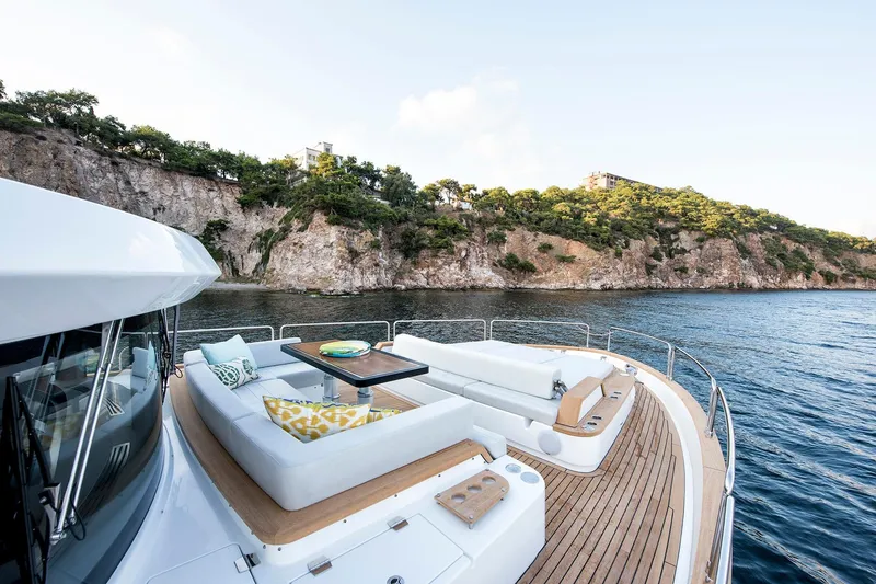 Slide: The Image of Luxurious Sirena 68 yacht deck with seating, overlooking scenic rocky coastline, 2026 model. - 13