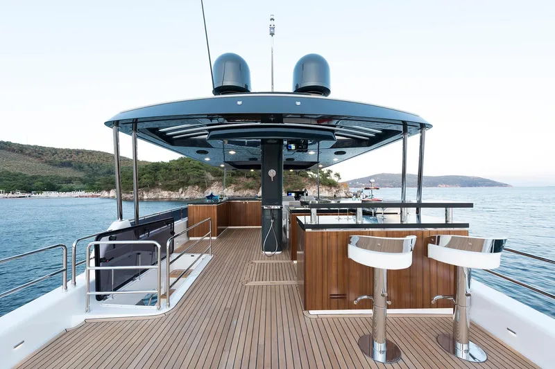 Slide: The Image of Luxurious 2026 Sirena 68 yacht deck with bar stools, overlooking serene coastal waters. - 32