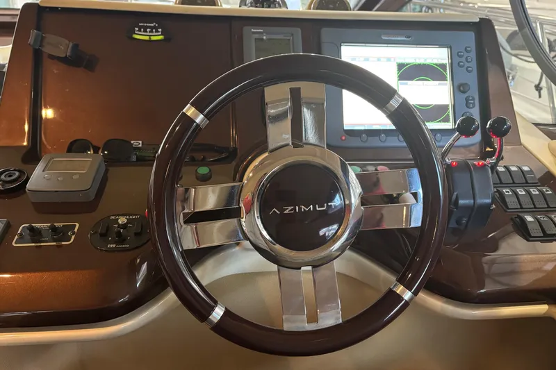 Slide: The Image of Steering wheel and dashboard of a 2008 Azimut 47 yacht, featuring navigation controls. - 18
