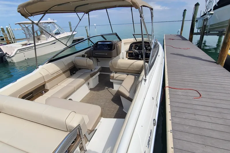 Slide: The Image of 2015 Formula 270 Bowrider docked, featuring spacious seating and canopy, in a serene marina setting. - 15