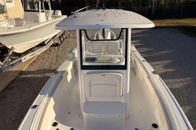 Slide: The Image of 2025 Sea Hunt Ultra 255 SE boat, white exterior, parked on gravel near another boat. - 6