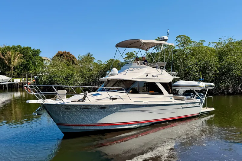 The Image of 2022 Cutwater C-32 CB boat cruising on a calm river, surrounded by lush greenery. - 1