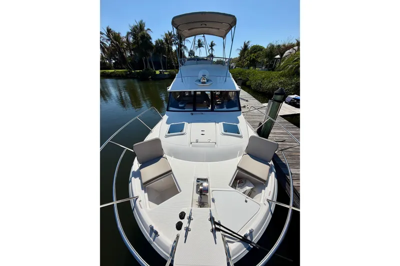 Slide: The Image of 2022 Cutwater C-32 CB boat docked, featuring spacious deck and seating, surrounded by lush greenery. - 10