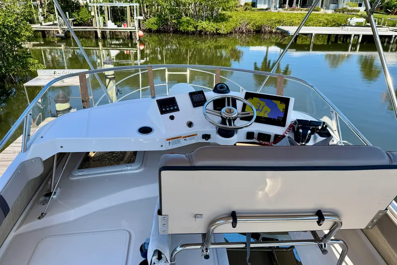Slide: The Image of 2022 Cutwater C-32 CB boat helm with navigation equipment and serene water backdrop. - 11