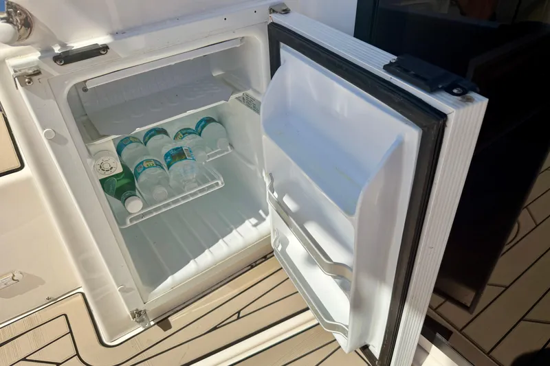 Slide: The Image of Open mini fridge on 2022 Cutwater C-32 CB boat, stocked with bottled water. - 27