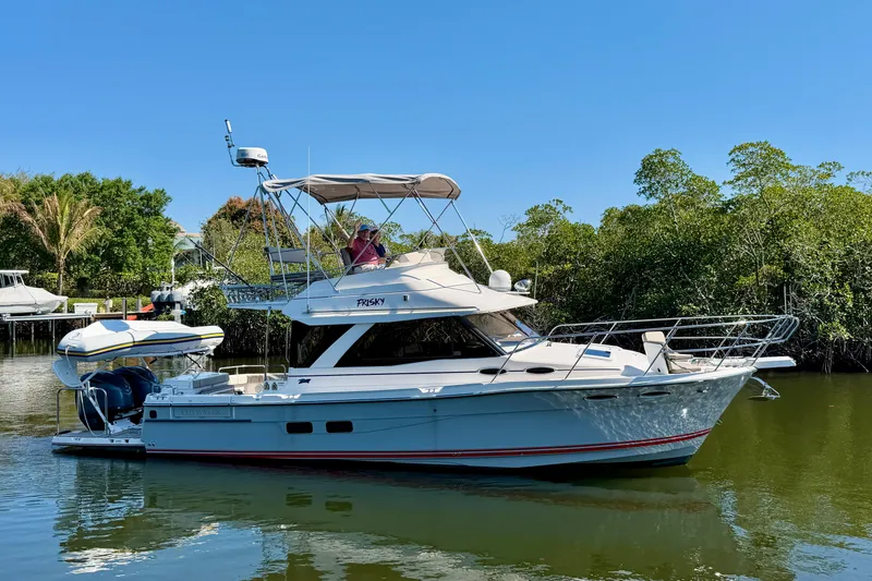 Slide: The Image of 2022 Cutwater C-32 CB boat on calm water, surrounded by lush greenery. - 7