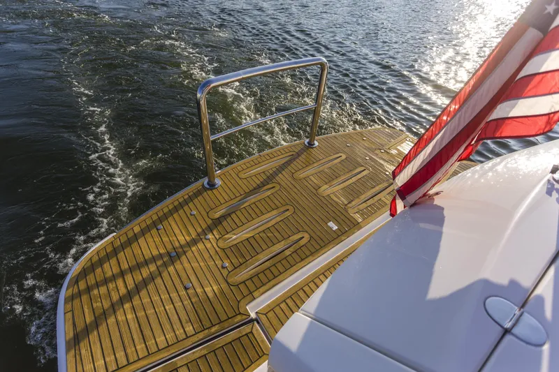 Slide: The Image of 2016 Riviera 5000 Sport Yacht with American flag on teak deck, cruising on water. - 10
